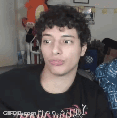 A Man With Curly Hair Is Wearing A Black Shirt That Says ' Nightmare ' GIF