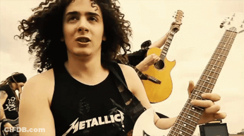 A Man With Curly Hair Is Wearing A Metallica Tank Top GIF