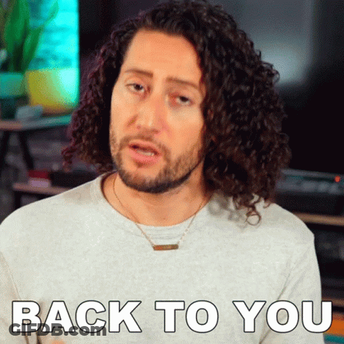 A Man With Curly Hair Is Wearing A Necklace And Says Back To You GIF
