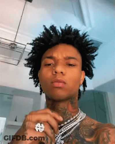 A Man With Curly Hair Is Wearing A Ring And A Necklace . GIF