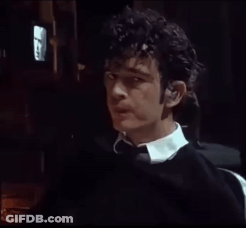 A Man With Curly Hair Is Wearing Ear Buds GIF
