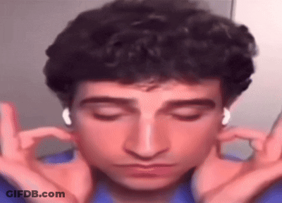 A Man With Curly Hair Is Wearing Headphones And Making A Funny Face With His Hands . GIF