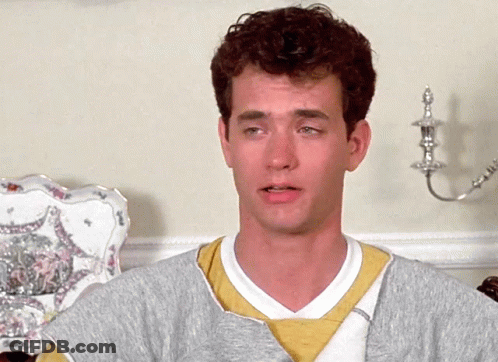 A Man With Curly Hair Wearing A Grey Sweater And A Yellow Sweatshirt GIF