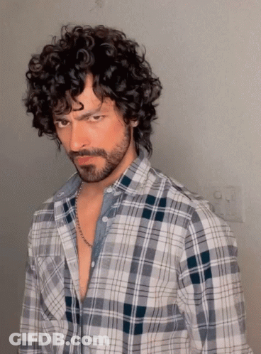 A Man With Curly Hair Wearing A Plaid Shirt GIF