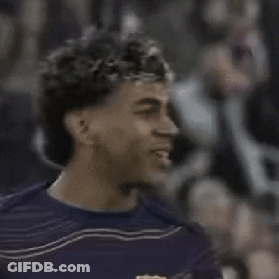 A Man With Curly Hair Wearing A Purple Shirt Is Smiling GIF