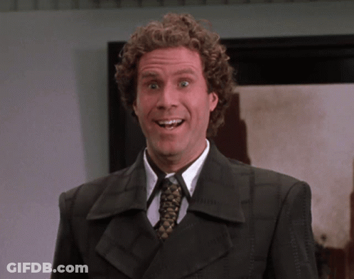 A Man With Curly Hair Wearing A Suit And Tie Smiles GIF