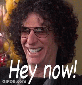 A Man With Curly Hair Wearing Glasses Is Smiling And Saying Hey Now . GIF