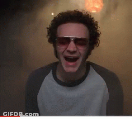 A Man With Curly Hair Wearing Sunglasses And A White Shirt With His Mouth Open GIF