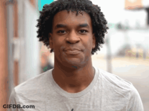 A Man With Curly Hair Wears A Grey Shirt GIF