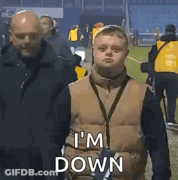 A Man With Down Syndrome Is Standing In Front Of A Group Of People On A Field . GIF