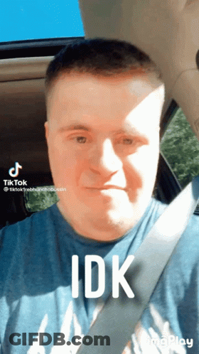 A Man With Down Syndrome Is Wearing A Blue Shirt And A Seat Belt GIF