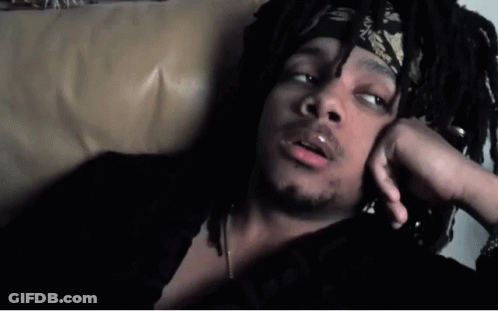 A Man With Dreadlocks And A Bandana On His Head Is Laying On A Couch GIF