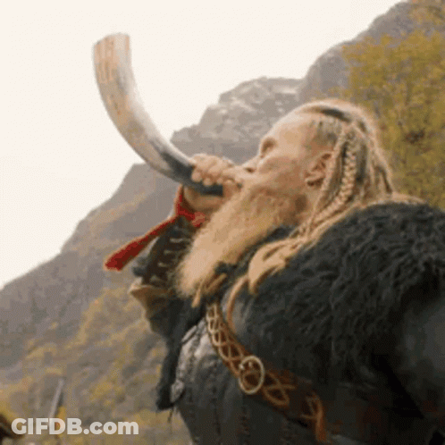 A Man With Dreadlocks And A Beard Is Blowing A Horn . GIF