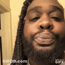 A Man With Dreadlocks And A Beard Is Blowing A Kiss At The Camera . GIF