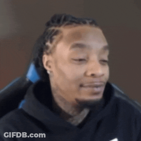 A Man With Dreadlocks And A Beard Is Sitting In A Chair Making A Funny Face . GIF