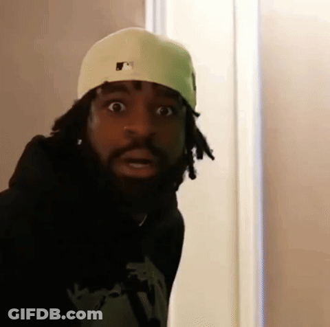 A Man With Dreadlocks And A Beard Wearing A White Hat And A Black Hoodie Is Making A Funny Face . GIF