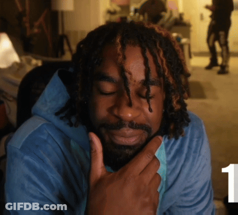 A Man With Dreadlocks And A Beard Wears A Blue Shirt GIF
