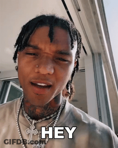 A Man With Dreadlocks And A Cross Necklace Says " Hey " GIF