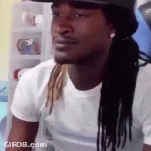 A Man With Dreadlocks And A Hat Is Wearing A White Shirt And A Hat . GIF