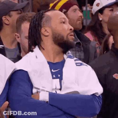 A Man With Dreadlocks And A Towel Around His Neck Is Watching A Basketball Game GIF