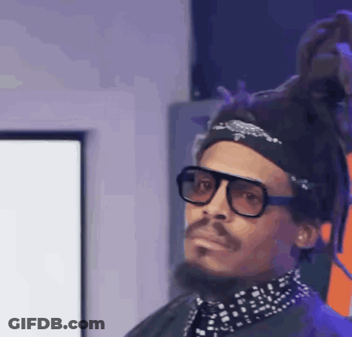 A Man With Dreadlocks And Glasses Is Wearing A Headband And A Bandana . GIF