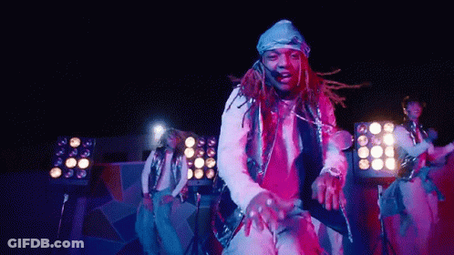 A Man With Dreadlocks Is Dancing On A Stage In Front Of A Crowd . GIF