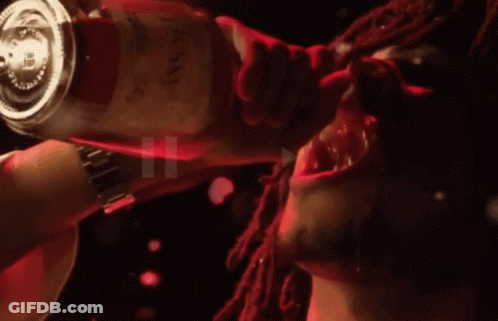 A Man With Dreadlocks Is Drinking From A Bottle That Says ' Red ' On It GIF