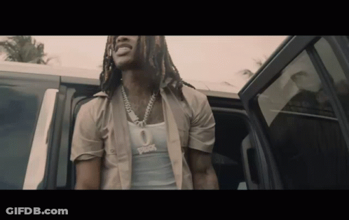 A Man With Dreadlocks Is Getting Out Of A Car And Wearing A Tank Top That Says ' Rick ' On It GIF