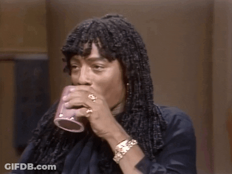 A Man With Dreadlocks Is Holding A Cup Of Coffee In His Hand . GIF