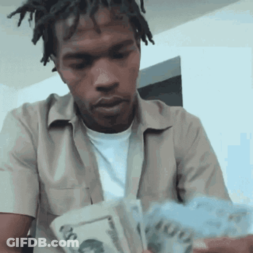 A Man With Dreadlocks Is Holding A Stack Of Money In His Hands . GIF