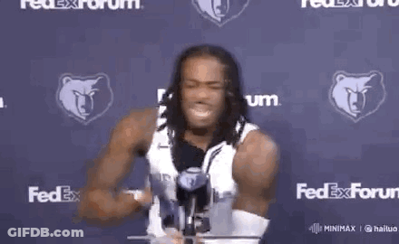 A Man With Dreadlocks Is Holding A Yellow Object In Front Of A Fedex Sign . GIF