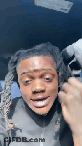 A Man With Dreadlocks Is Making A Funny Face While Sitting In A Car With His Mouth Open . GIF