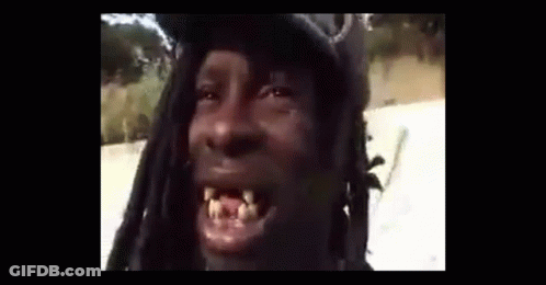 A Man With Dreadlocks Is Making A Funny Face While Wearing A Hat . GIF