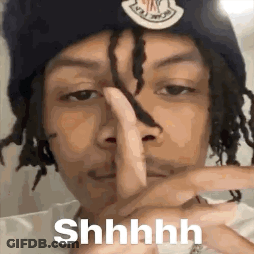A Man With Dreadlocks Is Making A Shhh Sign With His Finger . GIF