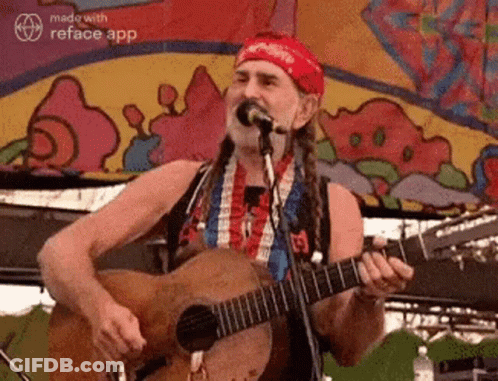 A Man With Dreadlocks Is Playing A Guitar And Singing Into A Microphone . GIF