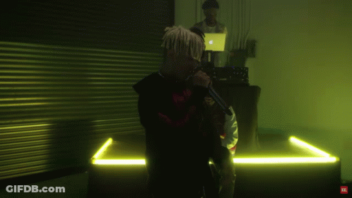 A Man With Dreadlocks Is Singing Into A Microphone With A Red Tnt Logo On The Bottom GIF