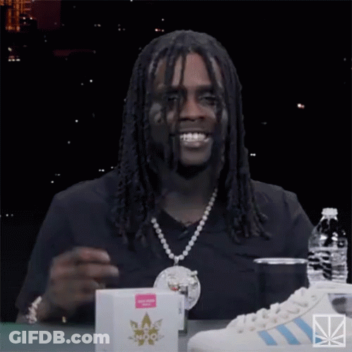 A Man With Dreadlocks Is Sitting At A Table With A Bottle Of Water And A Pair Of Adidas Sneakers GIF