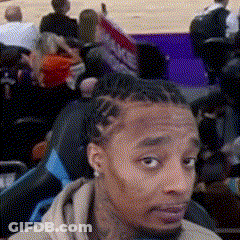A Man With Dreadlocks Is Sitting In A Stadium Watching A Basketball Game . GIF