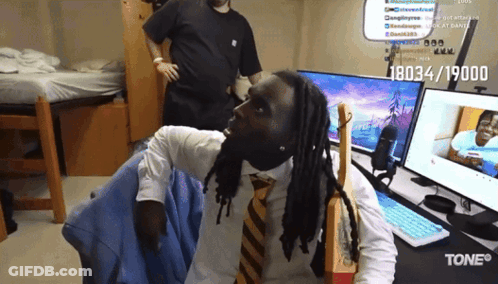 A Man With Dreadlocks Is Sitting In Front Of A Computer With The Number 18034/19000 On It GIF