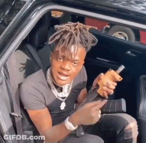 A Man With Dreadlocks Is Sitting In The Back Seat Of A Car Holding A Gun GIF