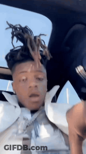 A Man With Dreadlocks Is Sitting In The Back Seat Of A Car With His Head In The Air . GIF