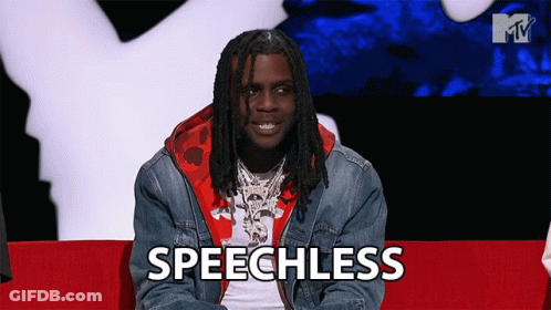 A Man With Dreadlocks Is Sitting On A Red Couch And The Word Speechless Is On The Screen In Front Of Him GIF