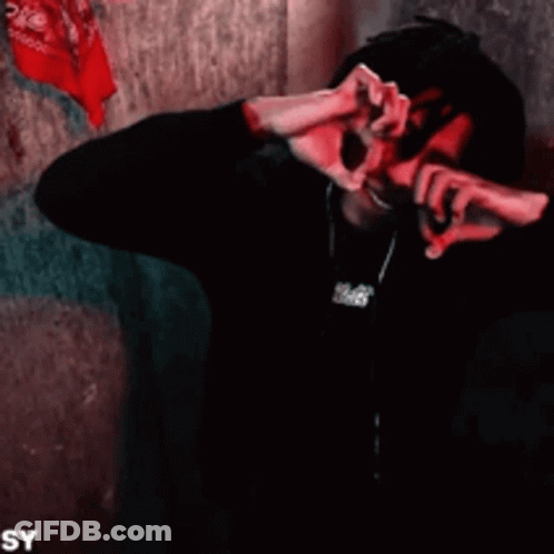 A Man With Dreadlocks Is Smiling And Making A Heart Shape With His Hands . GIF