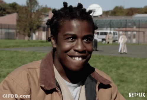 A Man With Dreadlocks Is Smiling In Front Of A Netflix Sign GIF