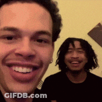 A Man With Dreadlocks Is Smiling Next To Another Man With Dreadlocks GIF