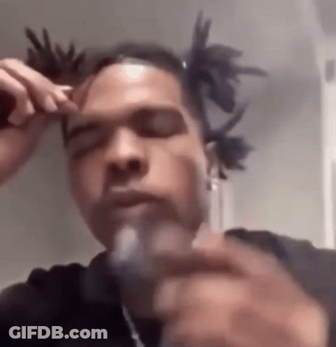 A Man With Dreadlocks Is Smoking A Cigarette While Wearing A Black Shirt . GIF