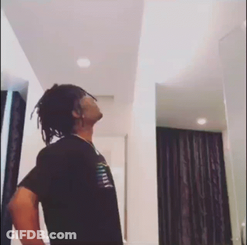 A Man With Dreadlocks Is Standing In A Room With His Hands On His Hips . GIF