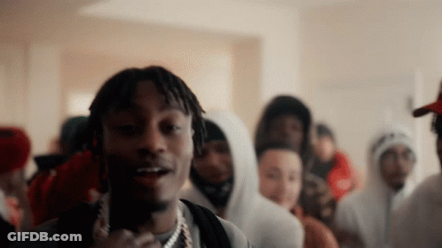 A Man With Dreadlocks Is Standing In Front Of A Crowd Of People Wearing Hoodies GIF