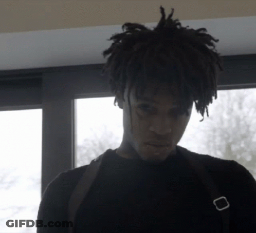A Man With Dreadlocks Is Wearing A Black Shirt And A Black Bag GIF