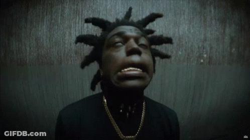 A Man With Dreadlocks Is Wearing A Black Shirt And Gold Chain GIF